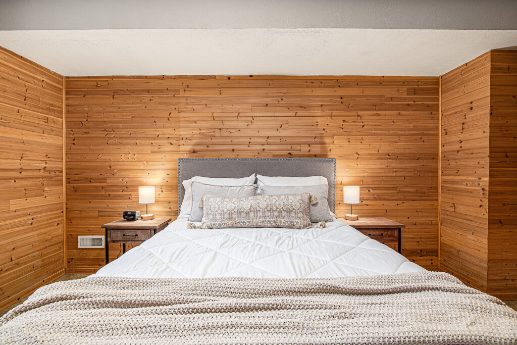 Cozy bedroom with wooden walls and white bedding