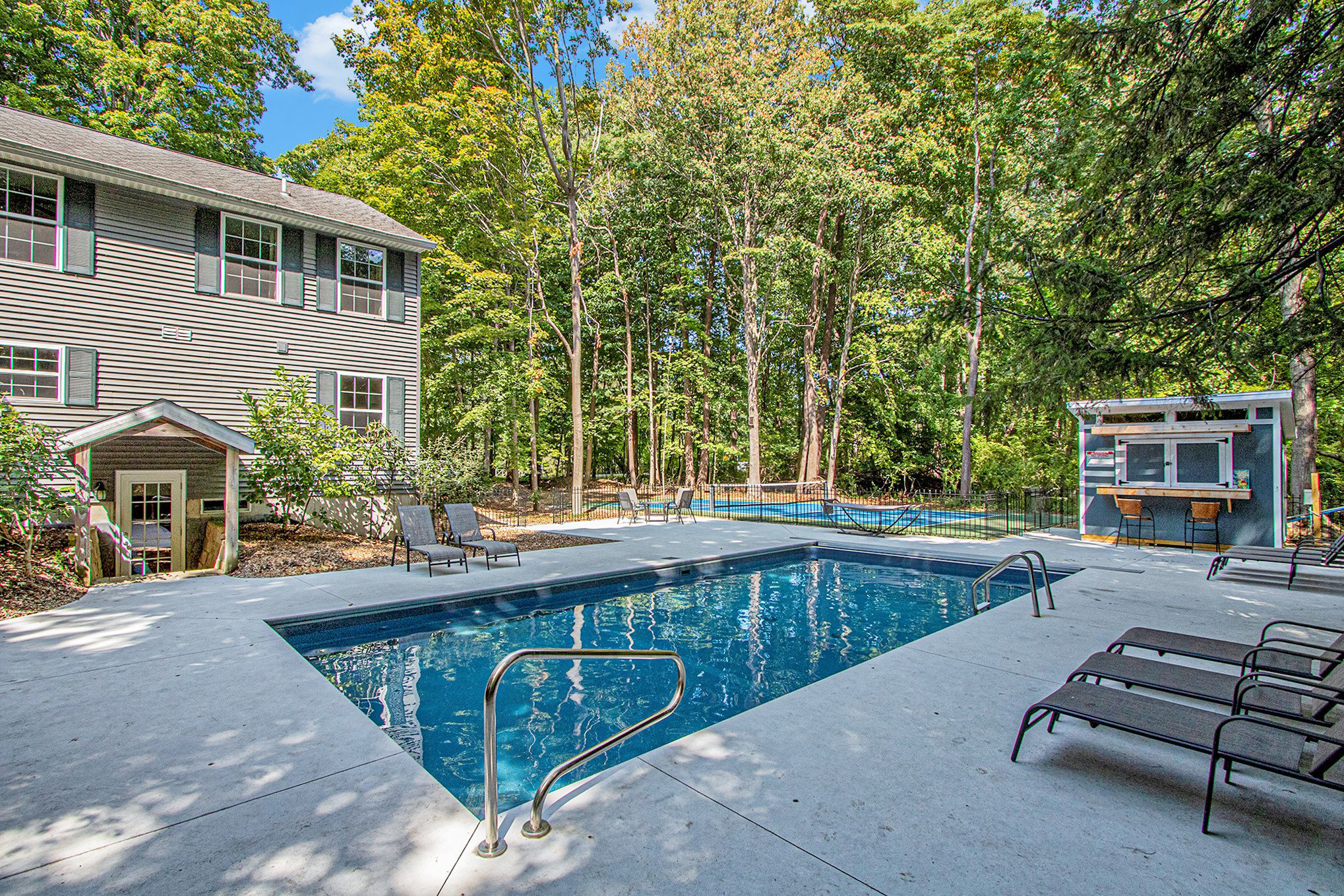 Backyard pool area with lounge chairs and trees