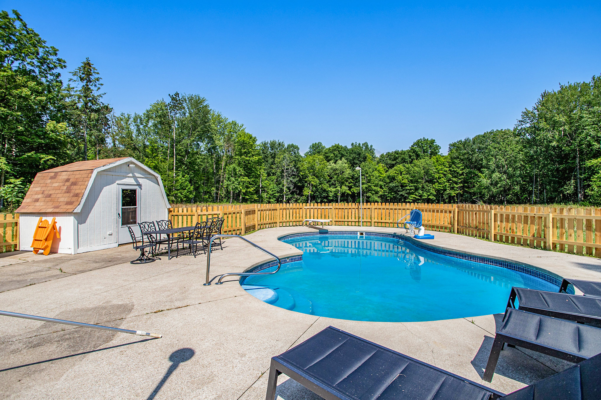 Fenced backyard pool with lounge chairs and shed