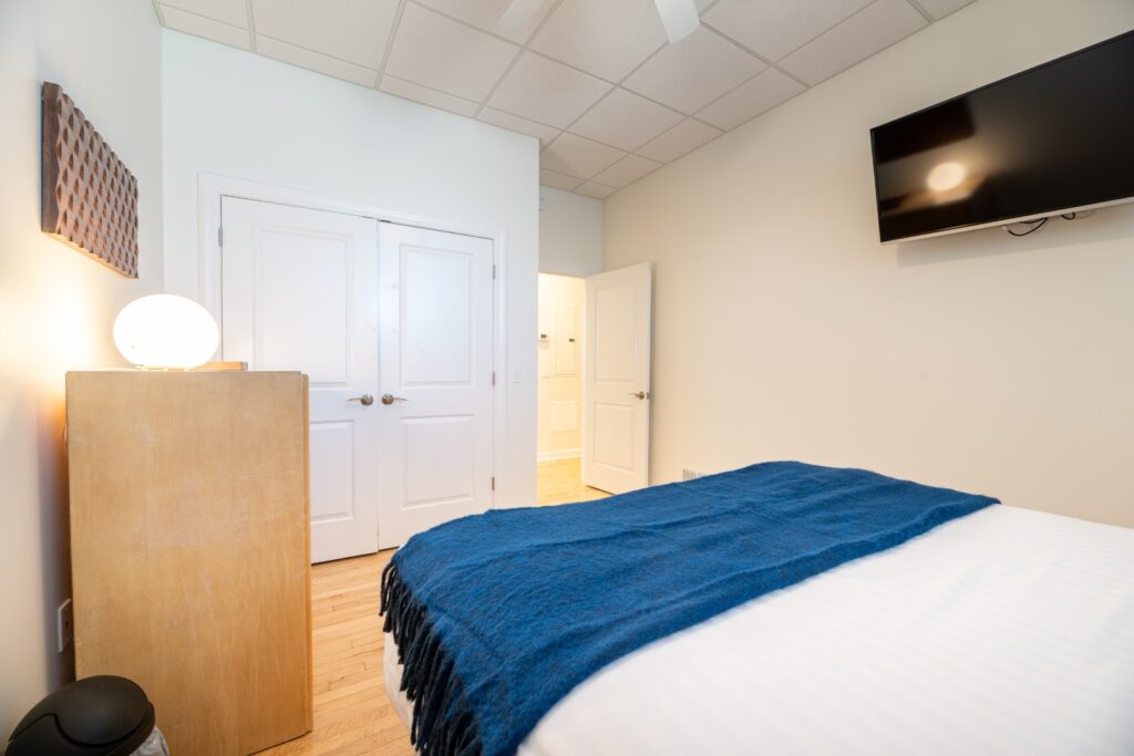 Modern bedroom with blue blanket and TV