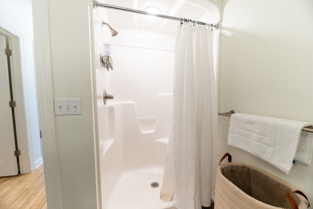 Bright bathroom shower with white curtain and towel