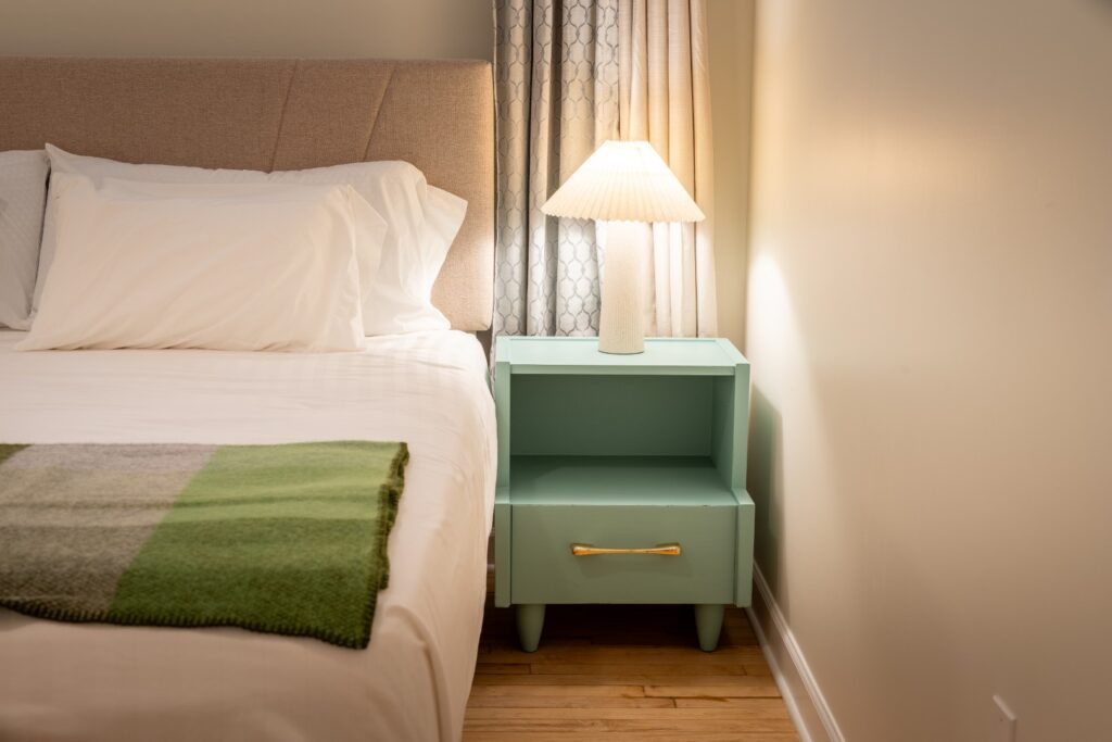 Bedside table with lamp beside cozy bed