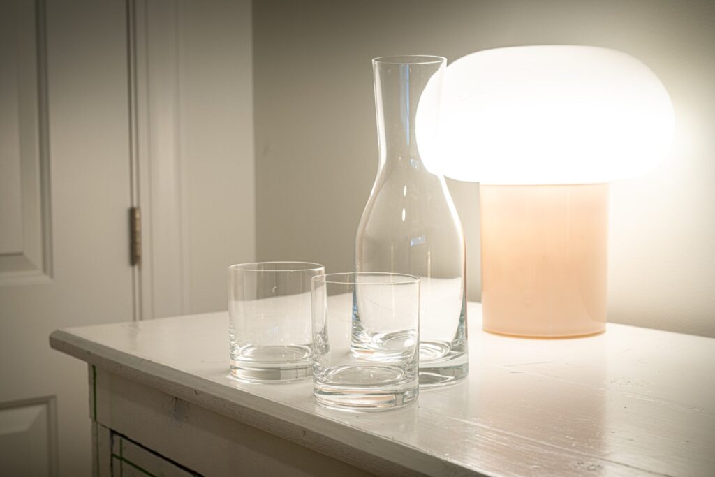 Glass carafe and cups beside table lamp