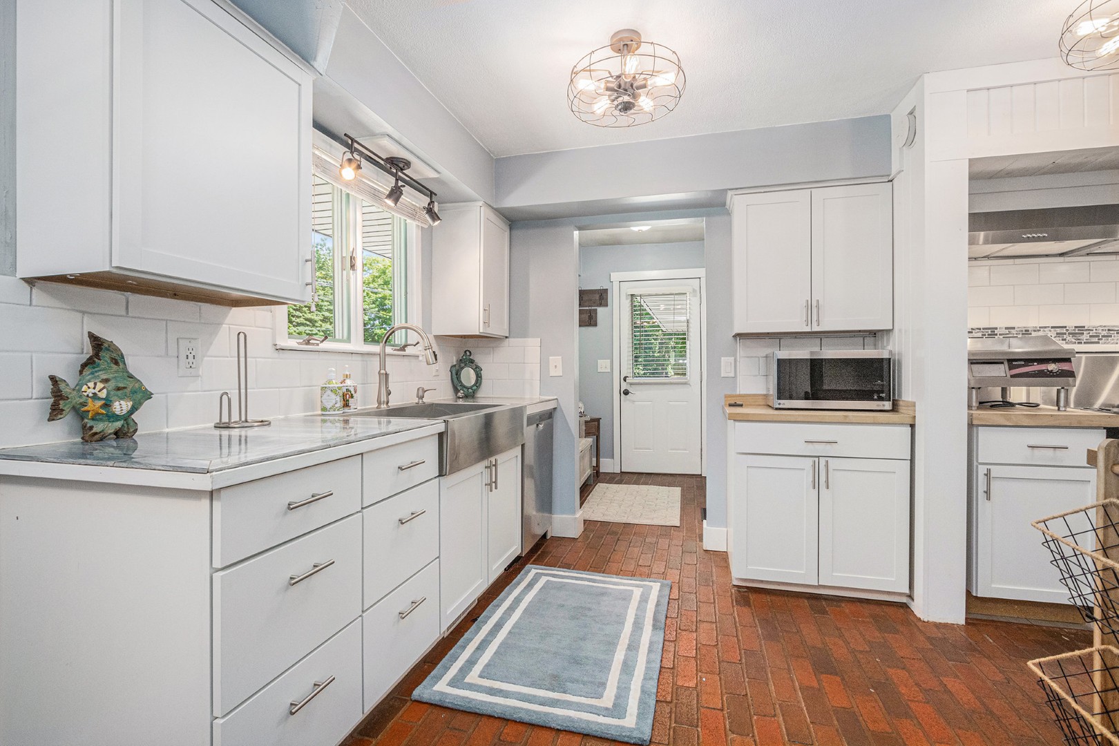 Modern kitchen with white cabinets and brick floor