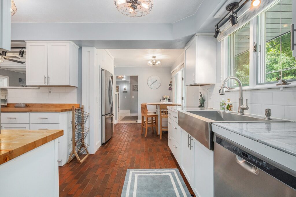 Modern kitchen with white cabinets and brick floor