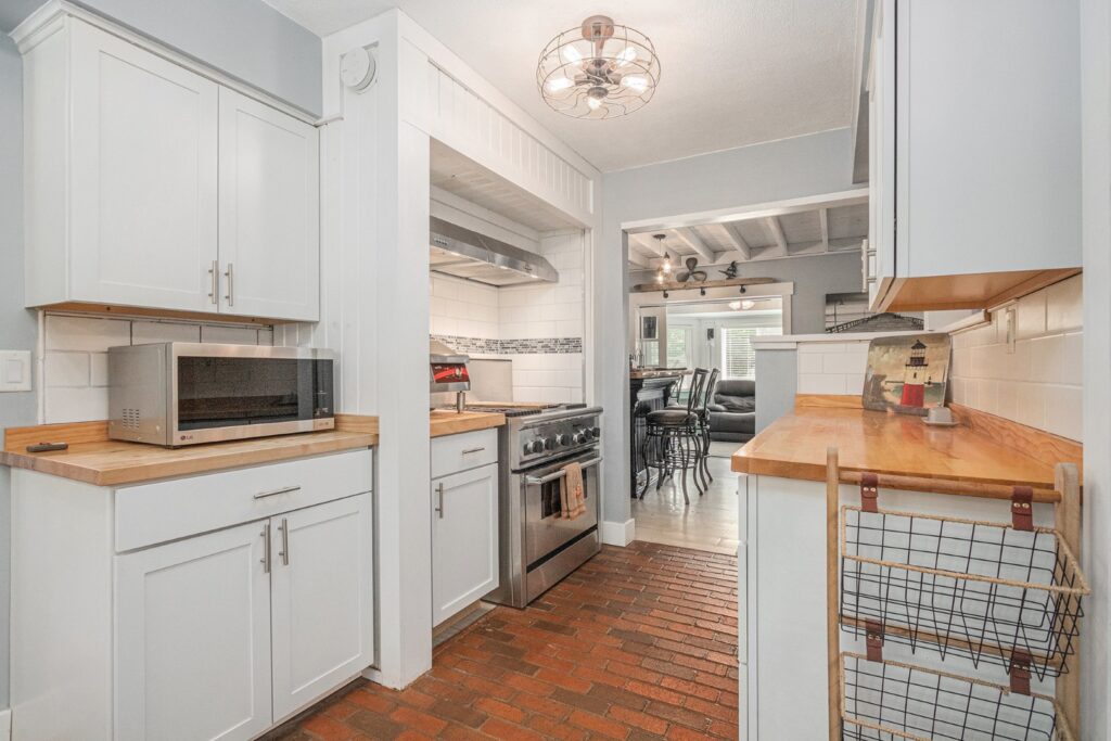 Modern kitchen with white cabinets and brick floor