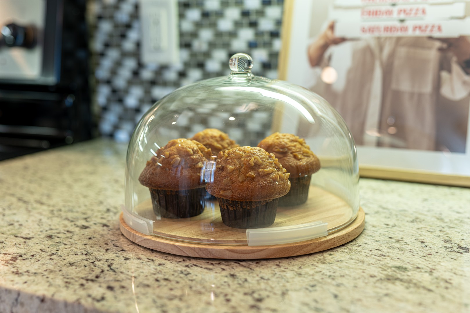 Fresh muffins under glass dome on counter
