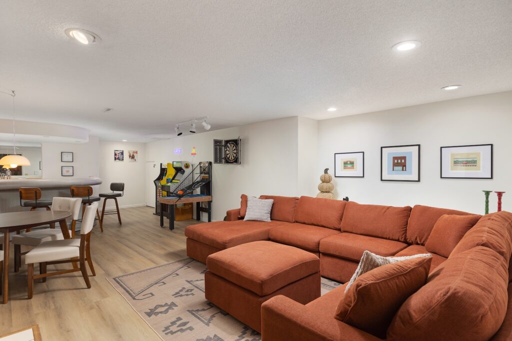 Modern basement with orange sectional and game area